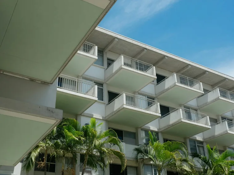 Looking up at a row of cantilevered concrete balconies on a mid century apartment building.